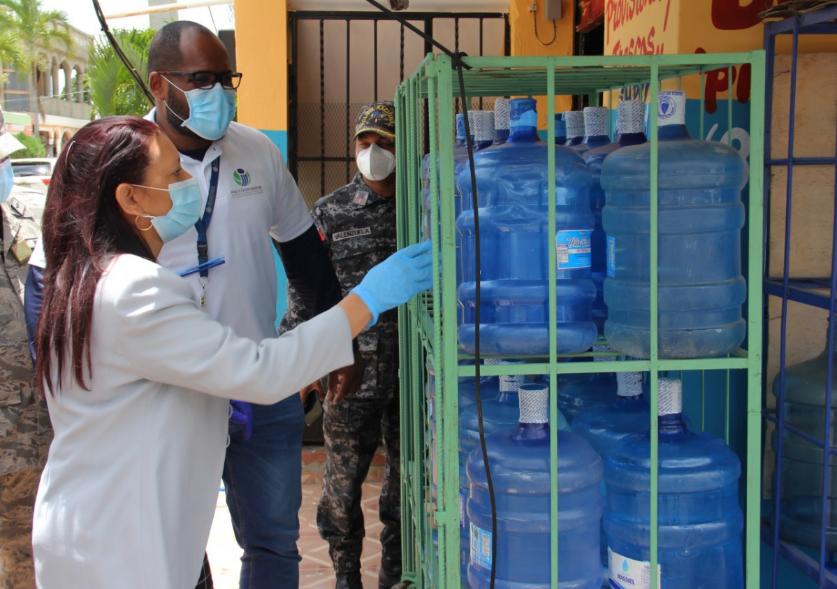 Thumbnail La subdirectora administrativa de Pro Consumidor Maria Teresa Paulino supervisa botellones de agua plasticos en un establecimiento comercial